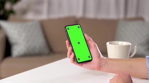 Hand Holding Smartphone with Green Screen at Home 144