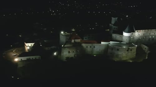 Aerial View of Illuminated Medieval Castle on Mountain in Small European City at Autumn Night