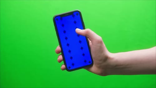 Closeup of Smartphone with Blue Screen Young Man Hands Holding Mobile Phone on Green Background
