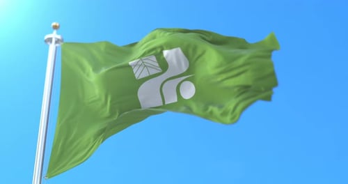 Green Flag with Environmental Symbol Waving Against Clear Blue Sky