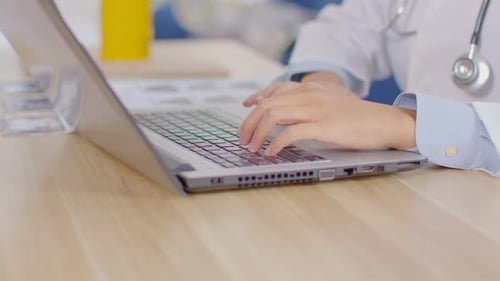 Close up hands of doctor typing on computer laptop at desk