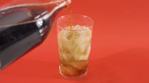 Dark Soda Pours Into Glass of Ice