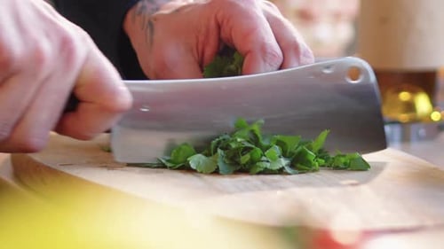 Hands Chopping Fresh Herbs with Knife on Wood