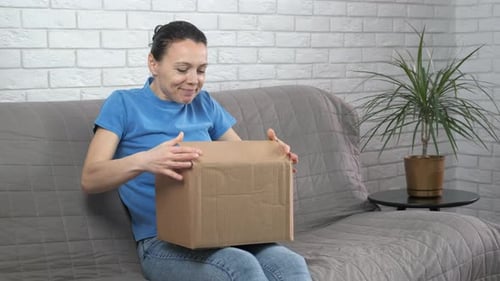 Woman Excitedly Opens Cardboard Box at Home
