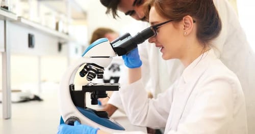 Junge Wissenschaftlerin schaut im Labor durchs Mikroskop