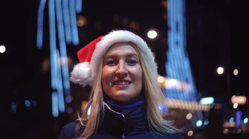 Smiling Woman in Santa Hat at Night
