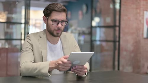 Man Using a Tablet at a Table Indoors