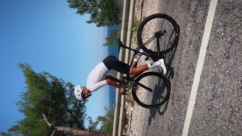 Cyclist with muscular fit body and white helmet riding road bicycle uphill in mountains