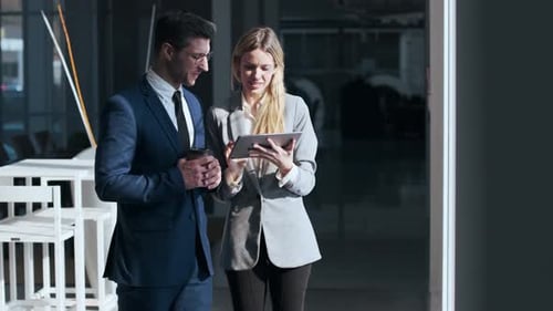 Businessman and woman standing in the street using digital tablet