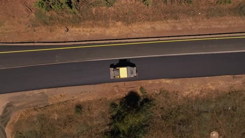 Road roller pressing fresh put Asphalt on a new road, Aerial follow footage.