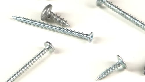 Silver Screws and Screwdriver on White Surface