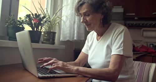 Senior Woman Types on a Laptop Indoors