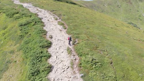 Aerial View of a Traveler with Backpack Climbing Along Mountain Slope. Epic Shot