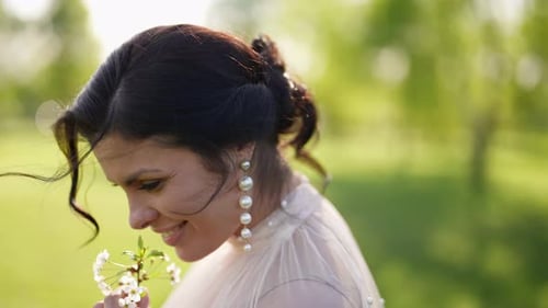 Elegant Woman Holding Flowers in Sunny Field