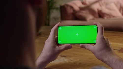 Handheld Camera Back View of Man at Phone with Green Screen for Copy Space