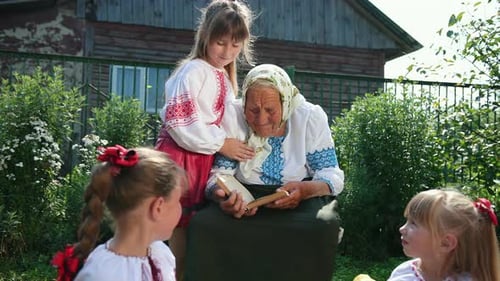 An Old Grandmother is Sitting on the Street and Reading a Book