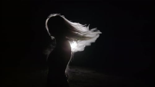 Woman Whips Long Hair Under Backlight at Night