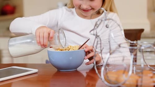 Child Pours Milk into Bowl of Cereal