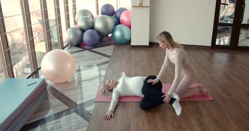 Woman Assisted Leg Stretch in Yoga Studio