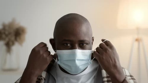 Adult Removing Blue Face Mask and Smiling