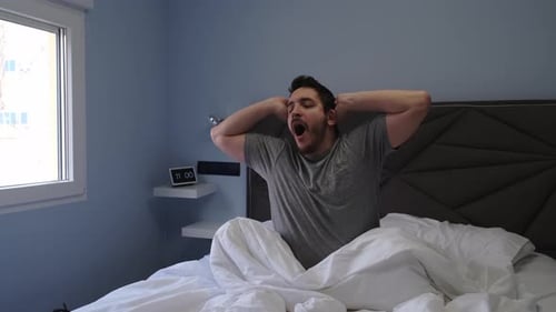 Man Waking Up and Stretching in Bed
