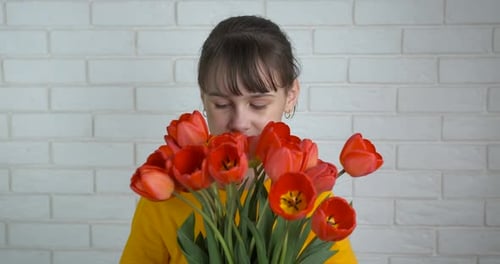 Girl Smelling Fresh Red Tulips Bouquet Indoors
