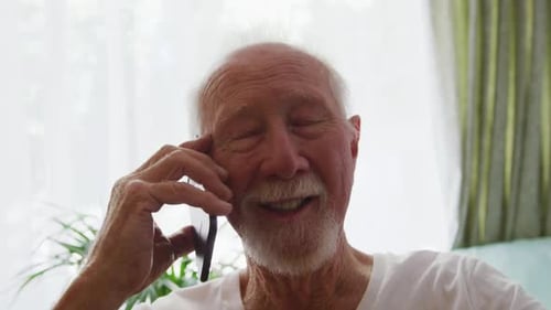 Happy Elderly Man Talking on Smartphone at Home
