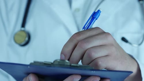 Doctor Writing Medical Notes on Clipboard