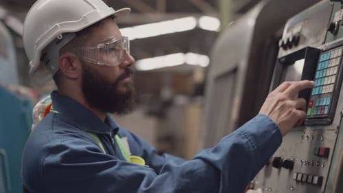 Männlicher Ingenieur in Sicherheitsuniform beim Gehen und Überprüfen auf der Fabrikmaschine