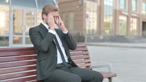 Stressed Man Sitting on a Bench With a Headache