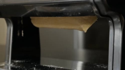 Dough Being Rolled Through Pasta Machine