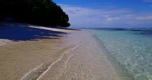 Tropical flying travel shot of a sunshine white sandy paradise beach and aqua blue ocean background