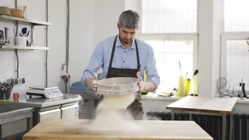 Man Sifting Flour onto Table for Baking