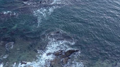Aerial View of Waves Crashing on Rocky Shoreline