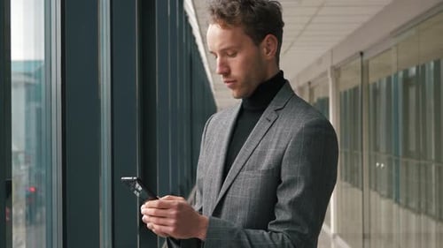 Business Man Using Mobile Phone Near Window