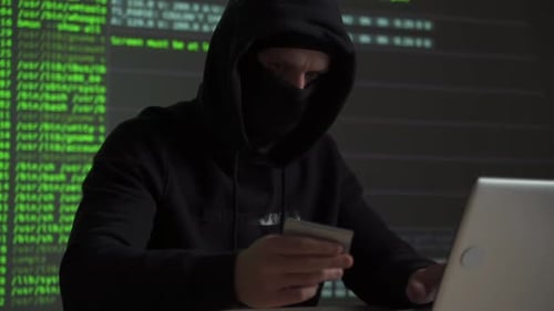Hacker de computador com cartão de crédito roubando dados de um laptop: conceito para segurança de rede e identidade