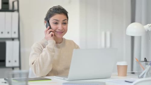 Young Adult Talking on the Phone at a Desk