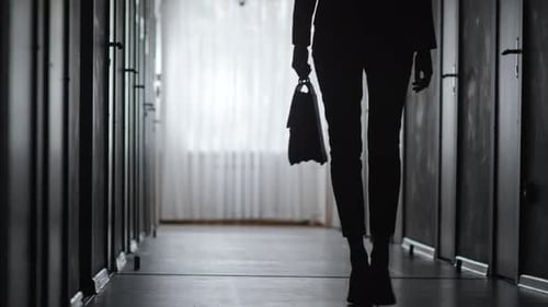 Silhouette of Woman Walking Down Dark Hallway
