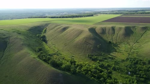 aerial view of the flight by drone over the hills with green farm fields.