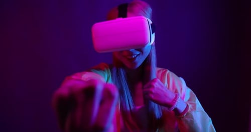Young Asian woman playing metaverse virtual reality digital technology game with VR goggle.