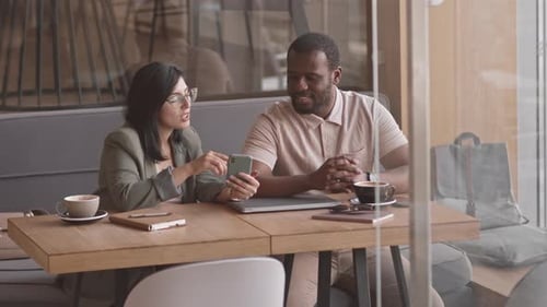 Two Multiethnic Colleagues Meeting in Cafe to Discuss Project