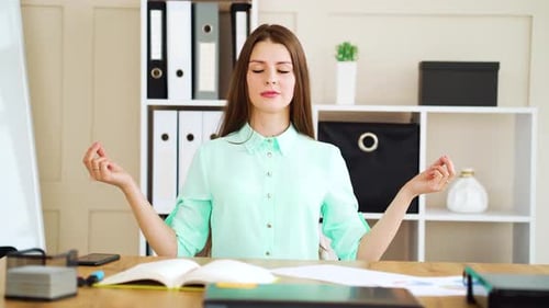 Young woman with closed eyes meditating in office