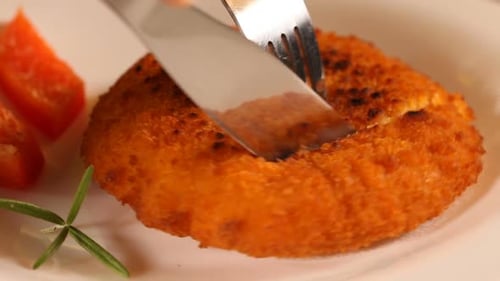 Breaded Cutlet Being Cut on a Plate