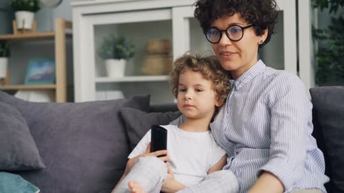 Mother and Child Relaxing on Couch with Phone
