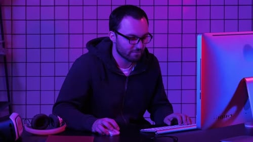 Man Uses Computer in Neon Lit Room