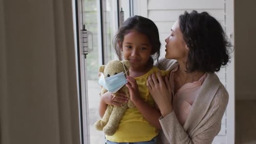 Loving Mother Embraces Child with Teddy Bear Indoors