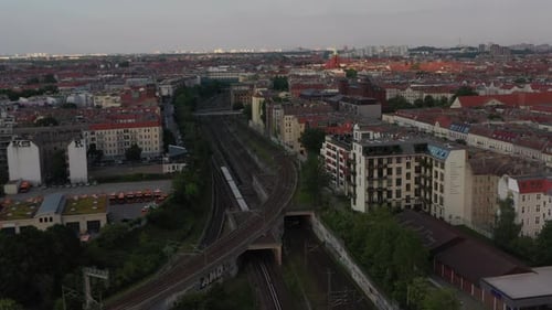 Luftaufnahme des Regionalzuges, der auf Bahngleisen zwischen Wohnhäusern in der Stadt fährt