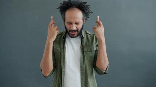 Man Crossing Fingers and Talking to Camera