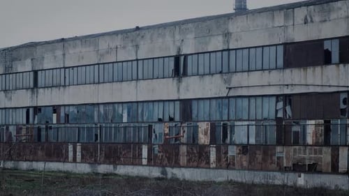 La fachada de una antigua fábrica en ruinas con ventanas rotas