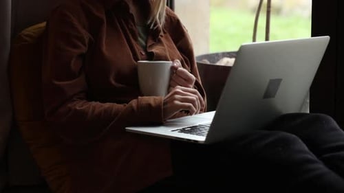 Person Using Laptop with Coffee Mug at Home